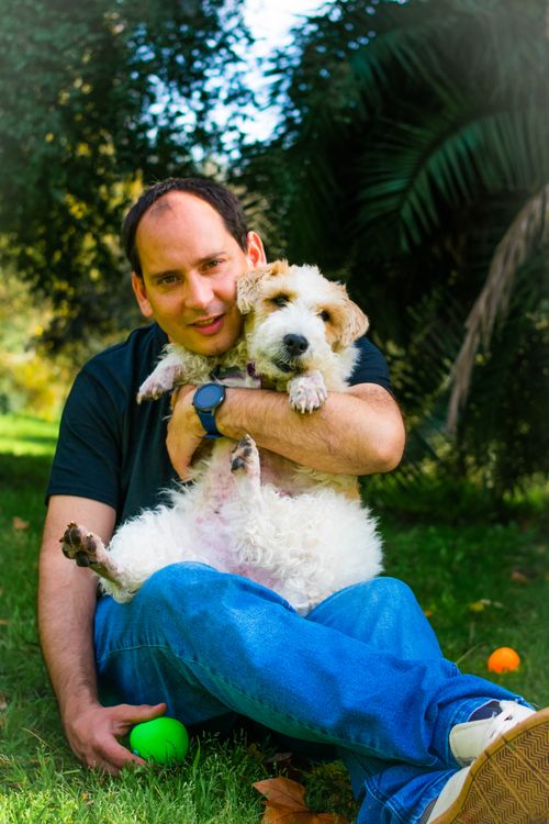 Free Cheerful man and fluffy dog playing in a sunny park, enjoying nature and companionship. Stock Photo