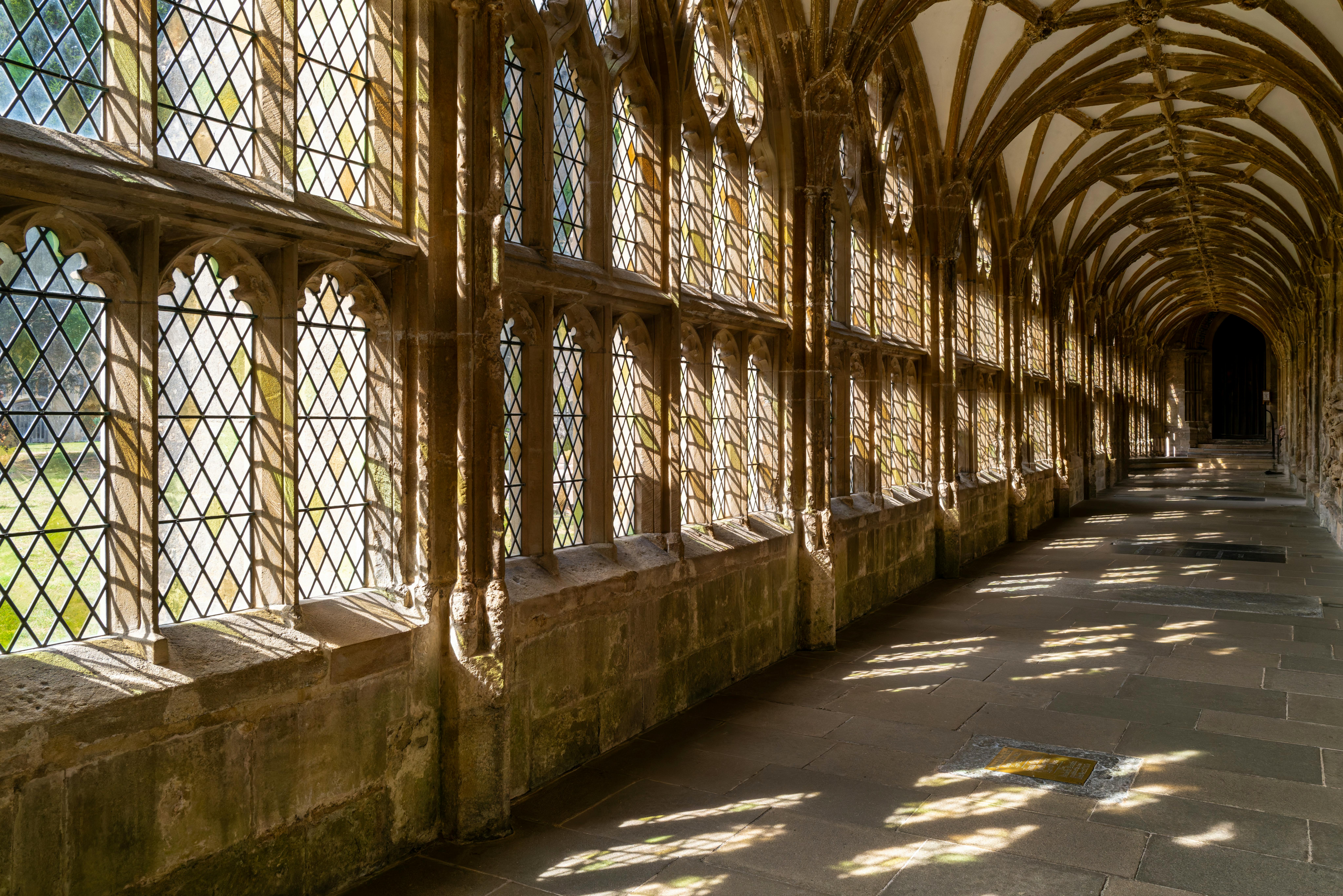 Sunlit cloister in Wells Cathedral showcasing gothic architecture with ornate stonework.