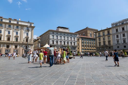A bustling scene of tourists in a historic square in Florence under a clear blue sky.