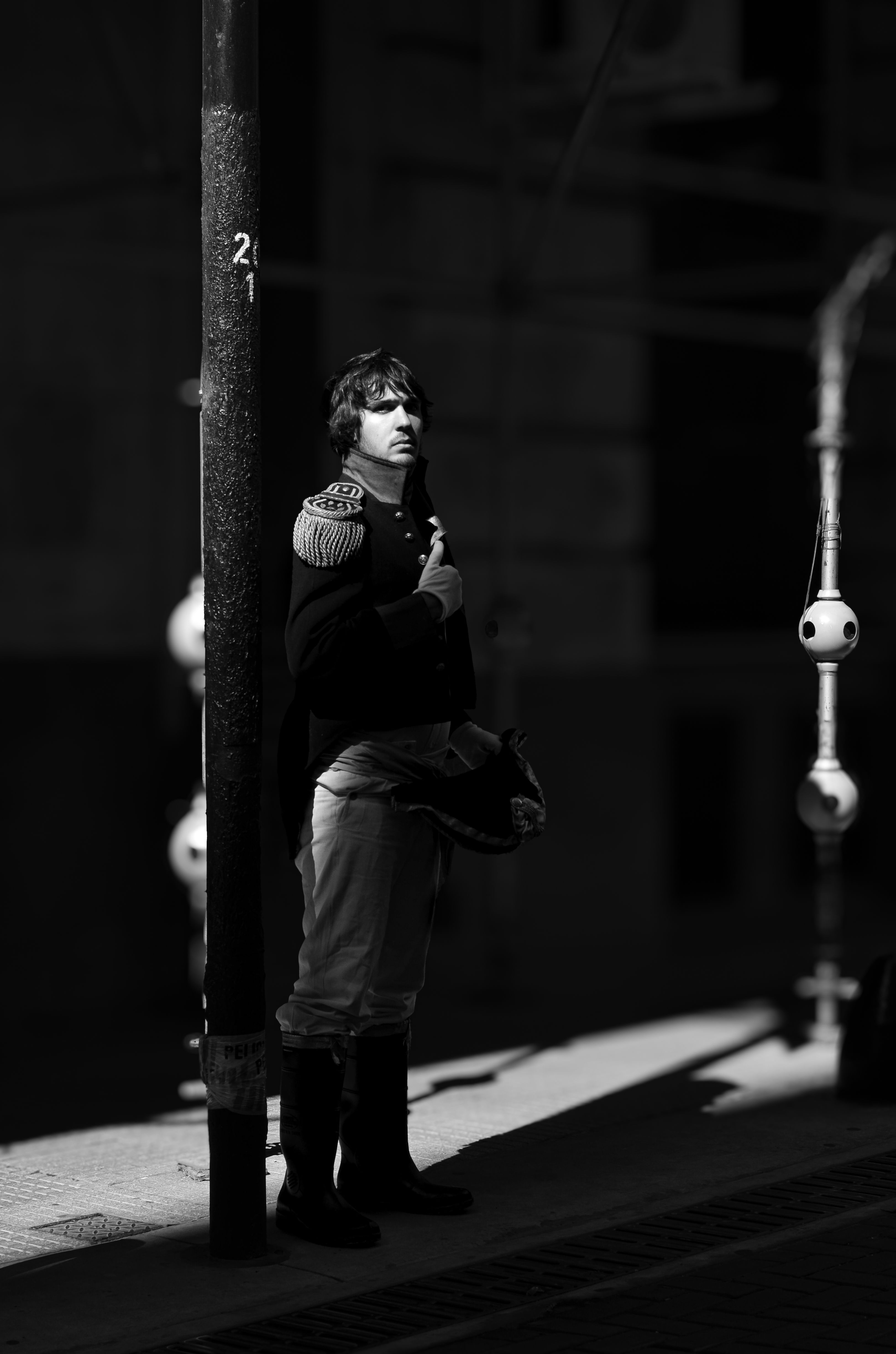 A man in historical attire stands by a lamppost, enveloped in dramatic lighting, capturing an essence of history on a Buenos Aires street.