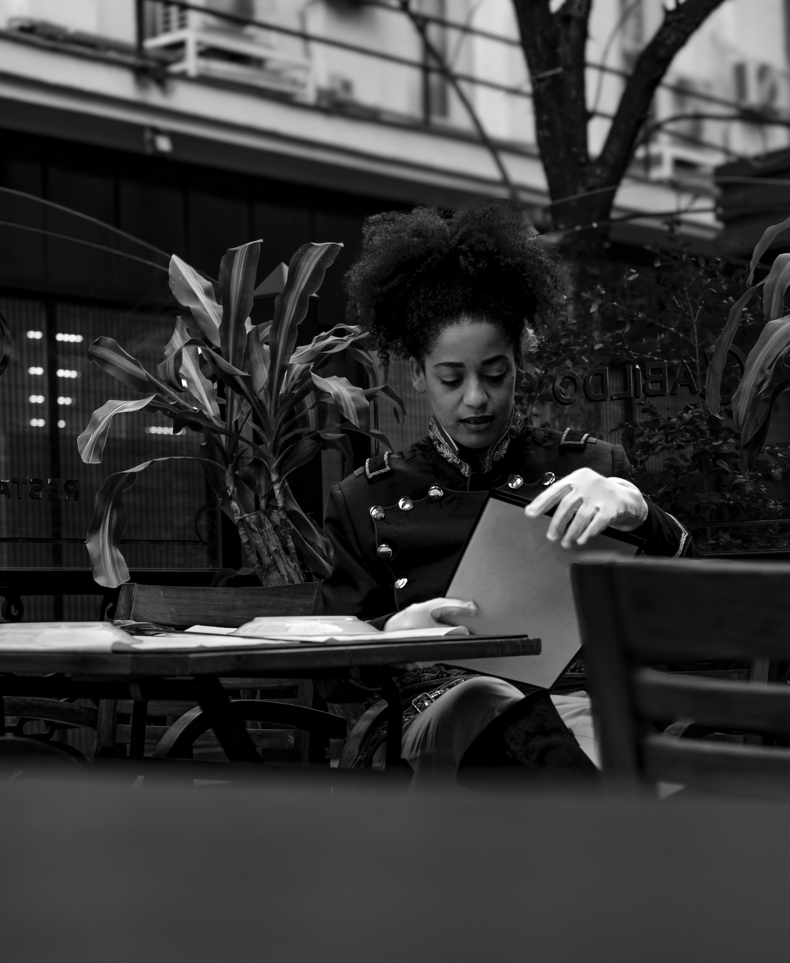 Gratis Elegante donna che legge in un bar all'aperto a Buenos Aires. Fotografia in bianco e nero. Foto a disposizione