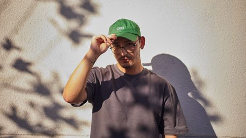 Free Portrait of a man outdoors in İstanbul with a green cap and glasses, casting an artistic shadow. Stock Photo