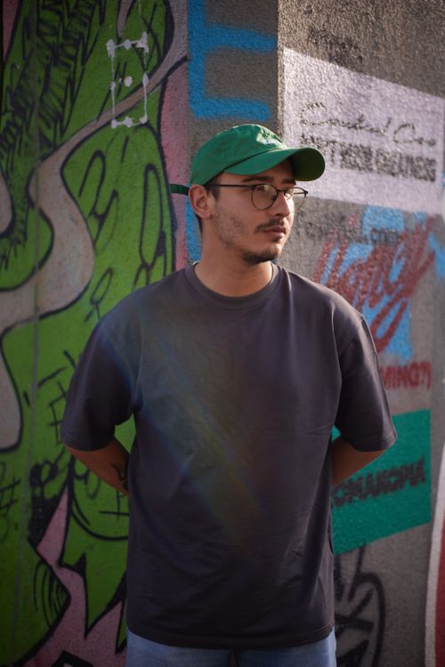 Free Stylish young man with glasses stands by a vibrant graffiti wall in Istanbul, creating a modern urban scene. Stock Photo