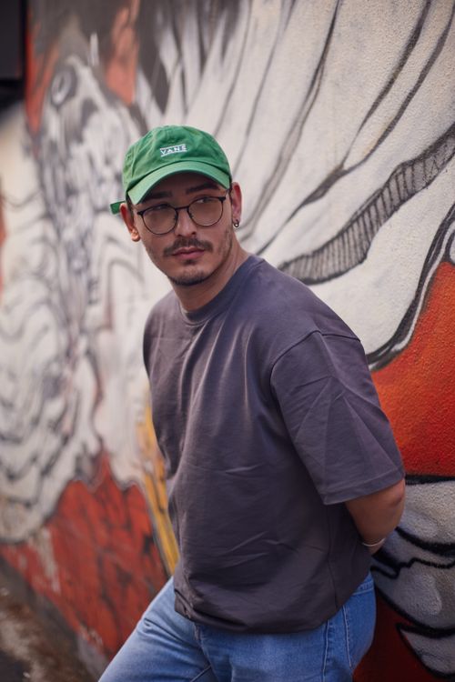Free Young man in casual wear leaning against vibrant street mural in İstanbul. Urban fashion and creative expression. Stock Photo