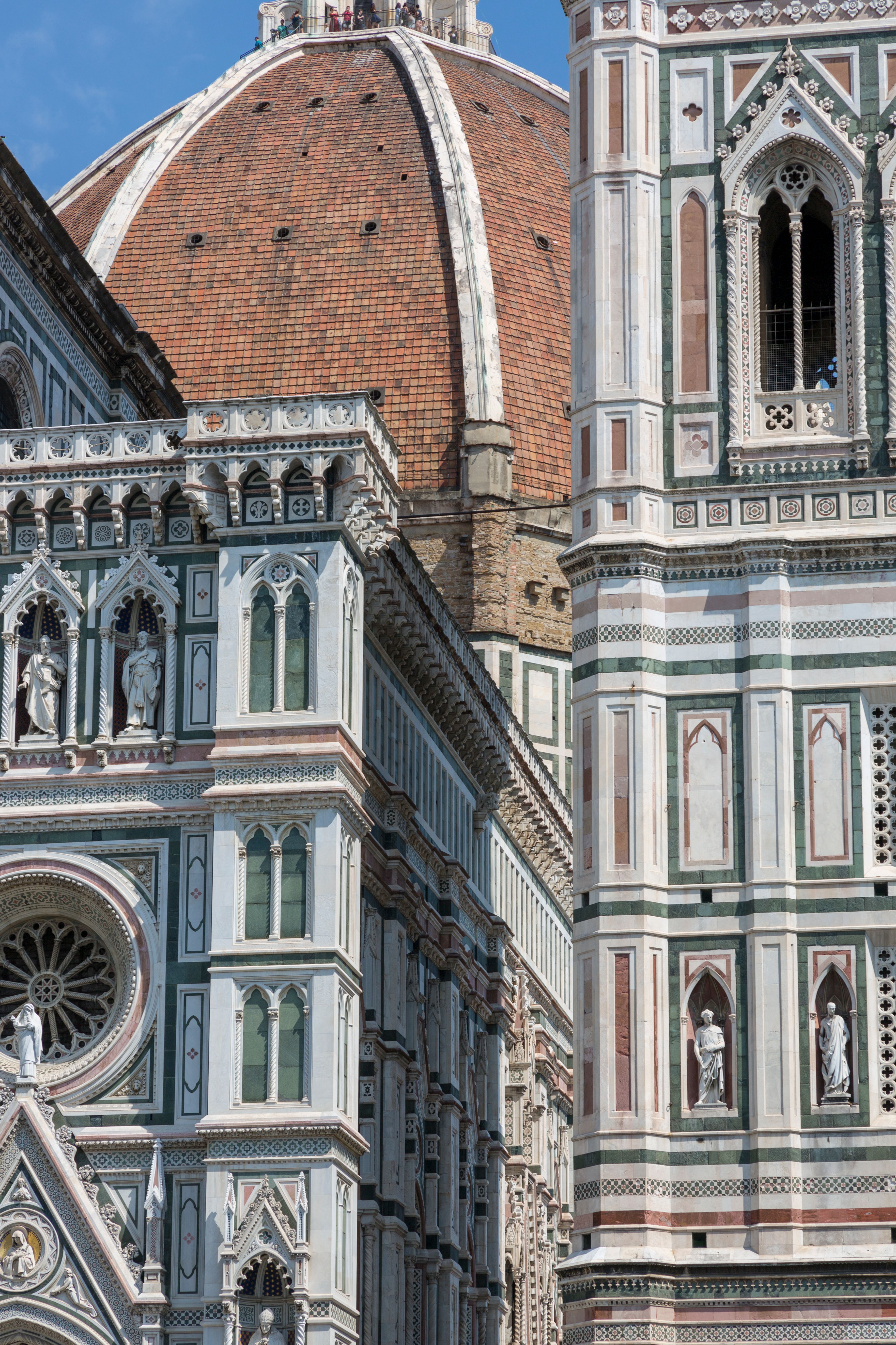 Detailed view of Florence Cathedral's intricate facade and iconic dome in sunlight.