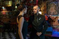 Elegant couple performs tango in a traditional Mar del Plata bar with live guitarist.