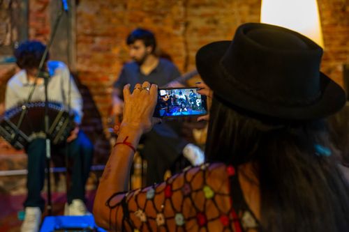 Free A woman photographs a live band performance in a cozy indoor setting in Mar del Plata, Argentina. Stock Photo