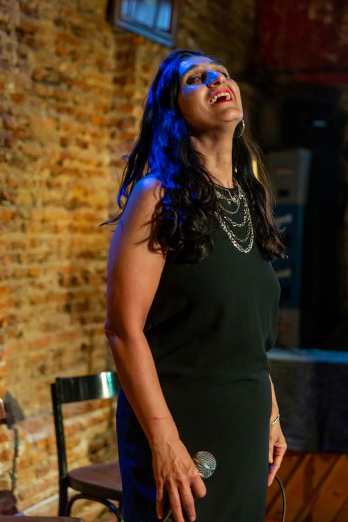 Free A woman passionately singing on stage at a brick-walled venue in Argentina. Stock Photo
