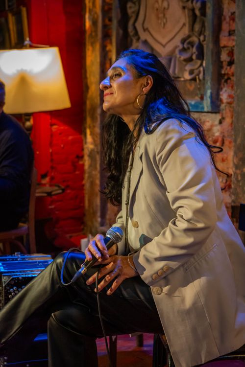 Free A woman sings passionately into a microphone in a warm, rustic bar. Stock Photo