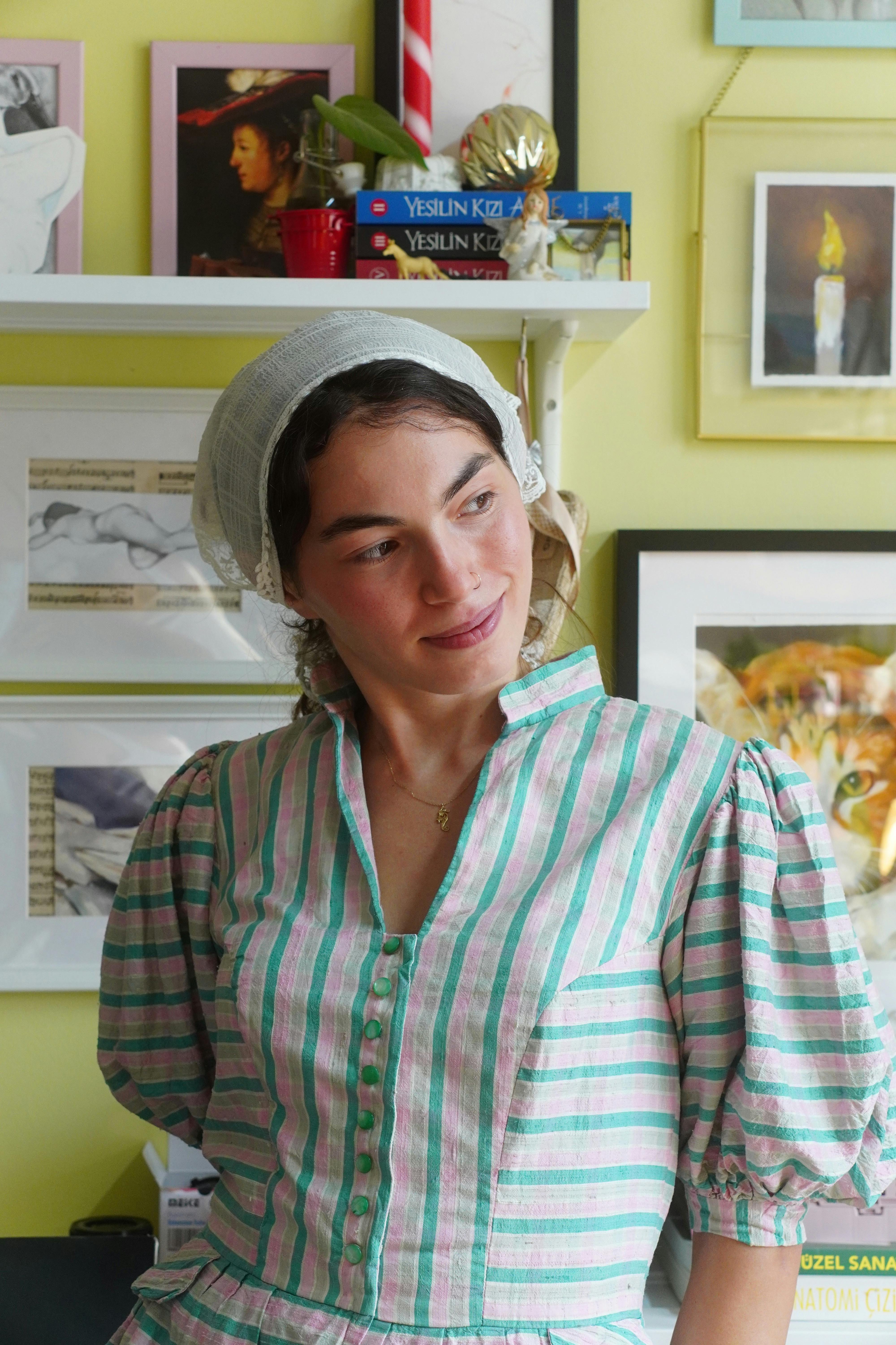 Woman in vintage dress indoors with art-filled background.