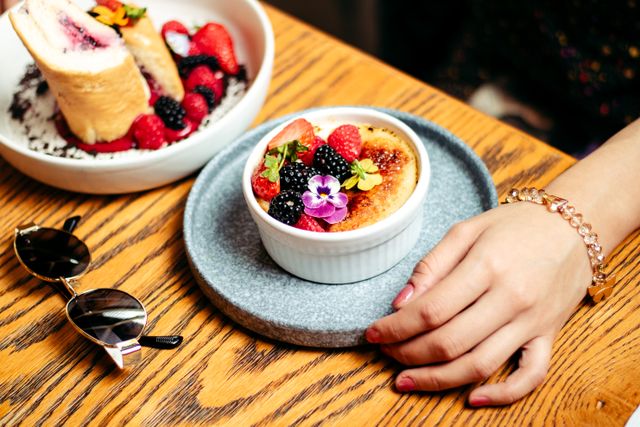 Close-up of crème brûlée topped with fresh berries and a flower, perfect for food lovers.