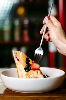 Indulge in a slice of gourmet cake with fresh berries, captured with a stylish fork in a modern setting.