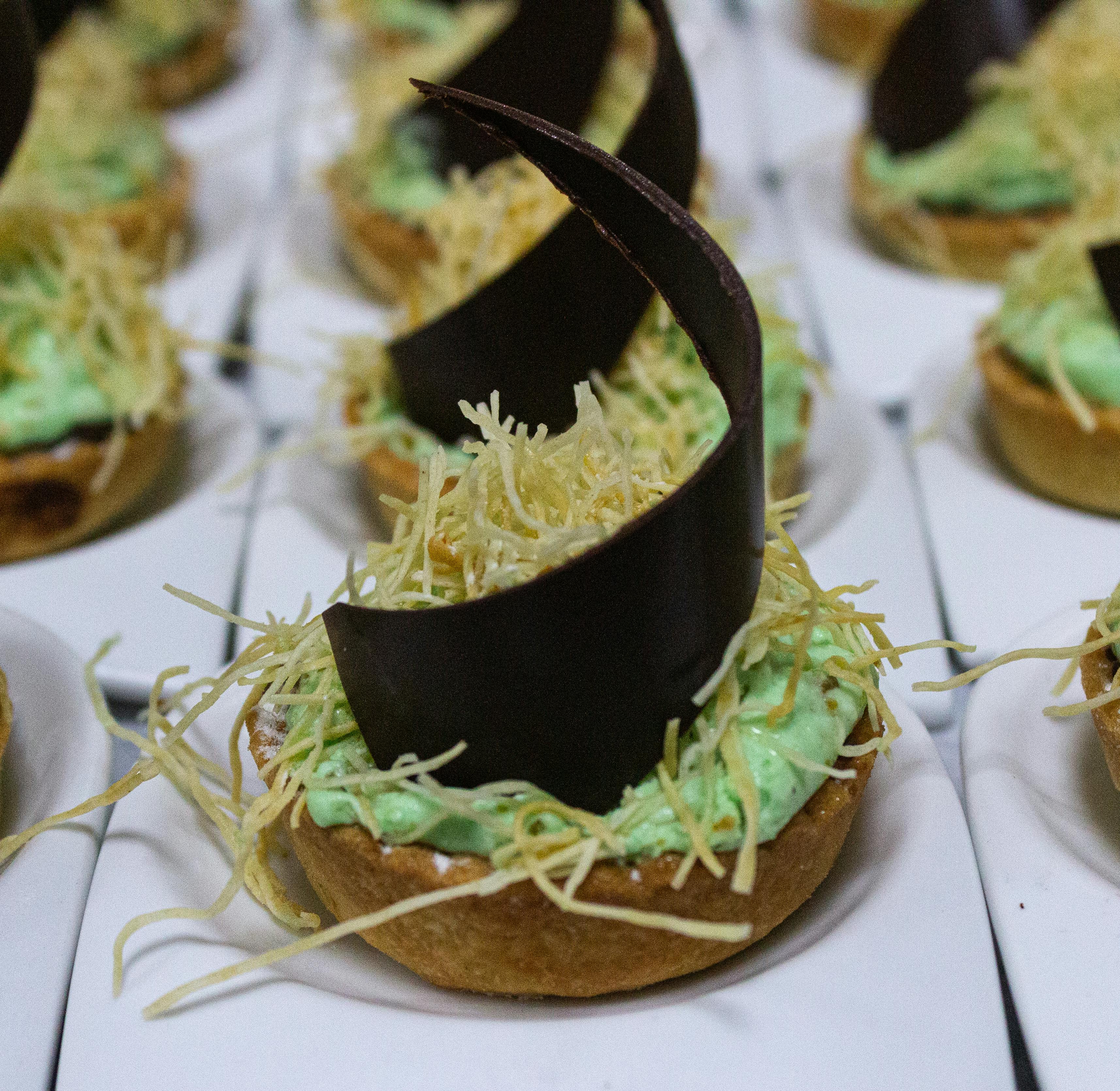 Tarteletes gourmet luxuosas com um delicado cacho de chocolate e creme, guarnecidas com fios crocantes.