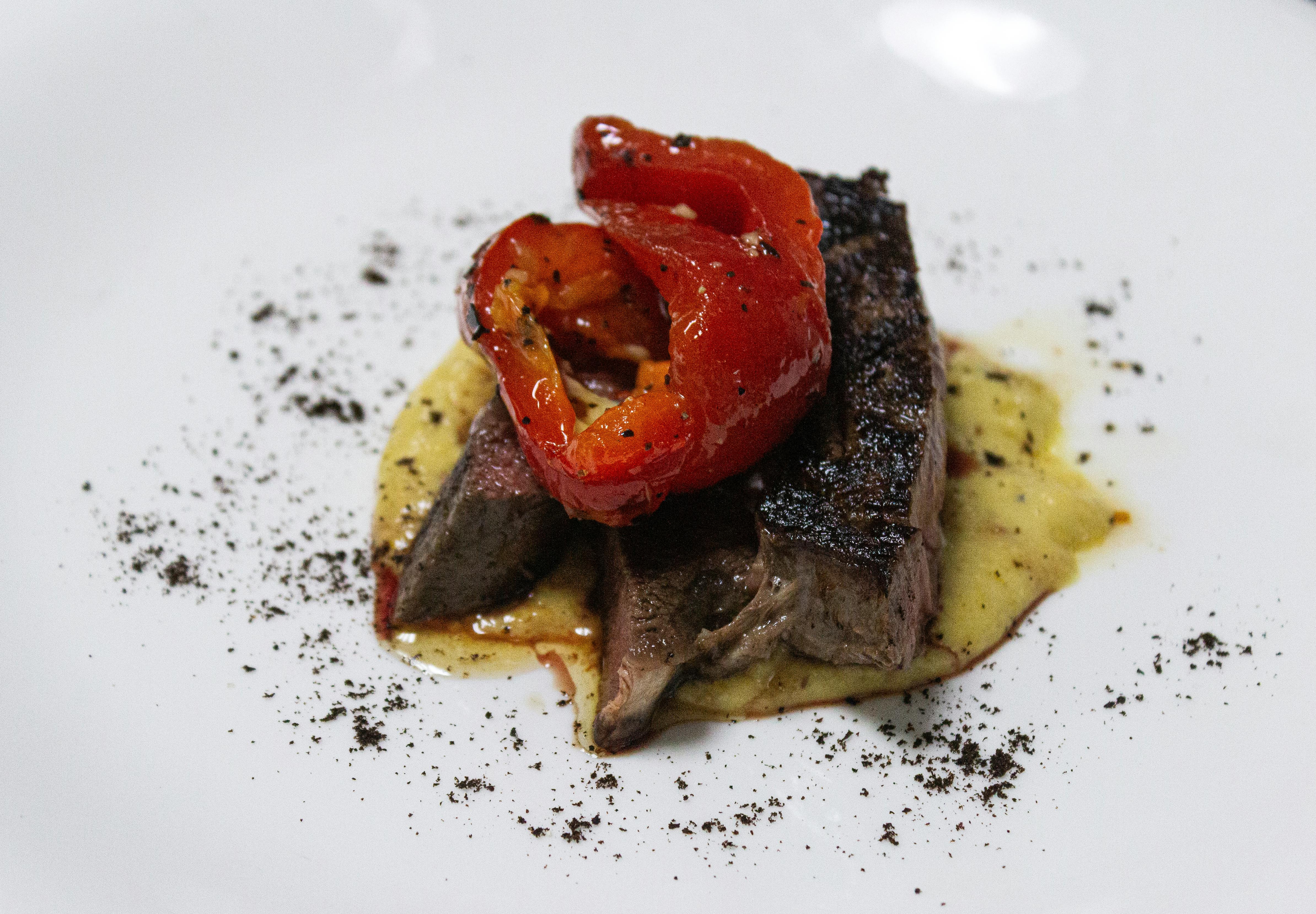Gastronomia de luxo: Sumptuous gourmet steak dish with roasted red peppers.