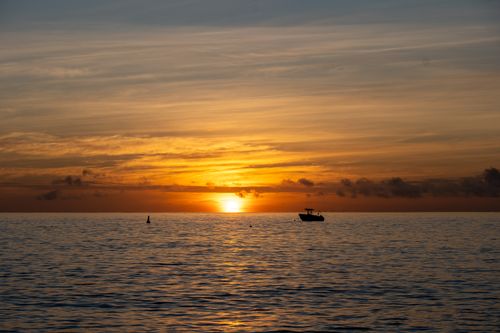 Free A peaceful sunrise over the ocean near Fiji's Kuata Island with a silhouette of a boat. Stock Photo