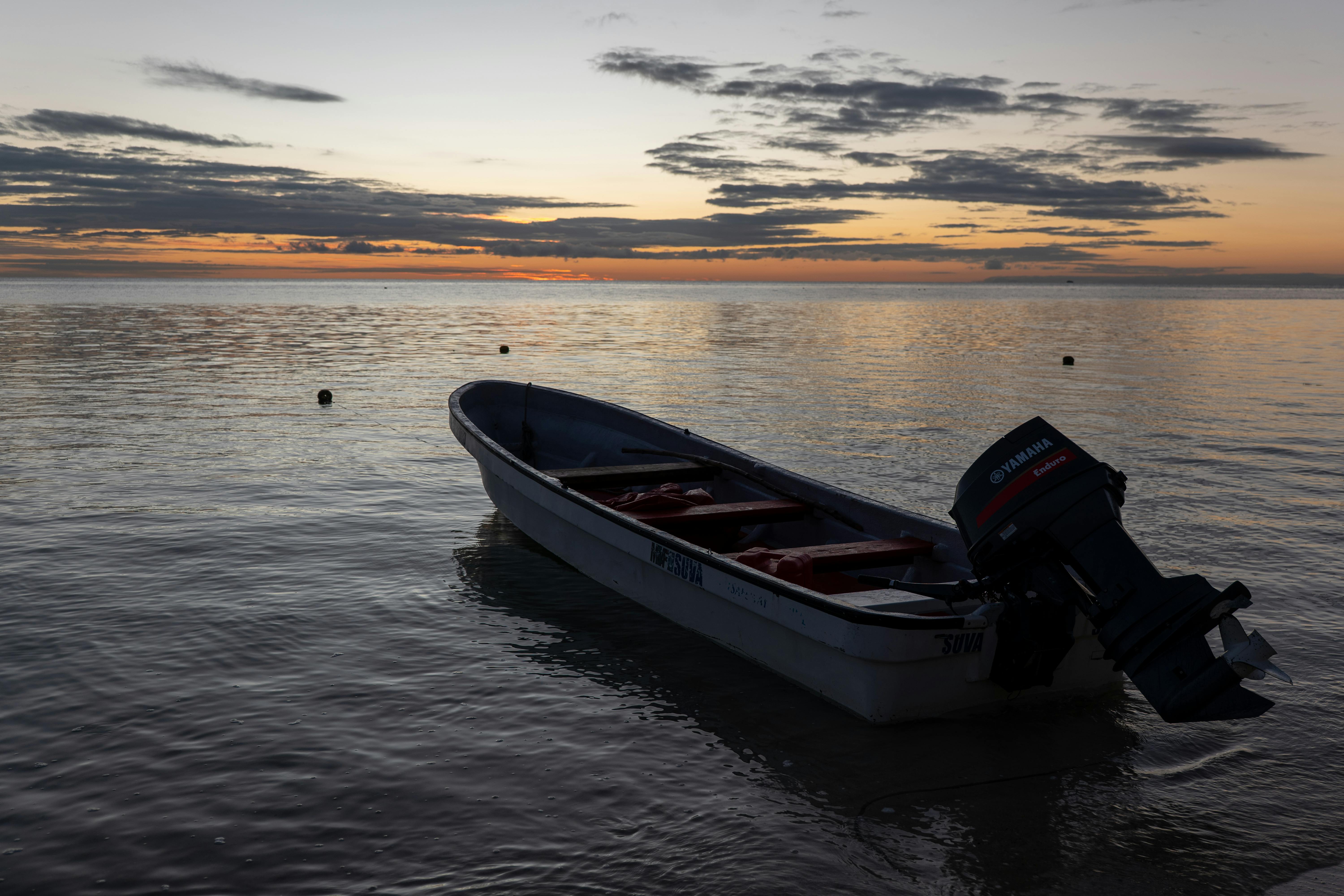 A serene scene of a boat anchored at sunset in the Yasawa Islands, Fiji, capturing the tranquil beauty of the tropical coastline. - Islas Yasawa