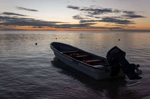 Free A serene scene of a boat anchored at sunset in the Yasawa Islands, Fiji, capturing the tranquil beauty of the tropical coastline. Stock Photo