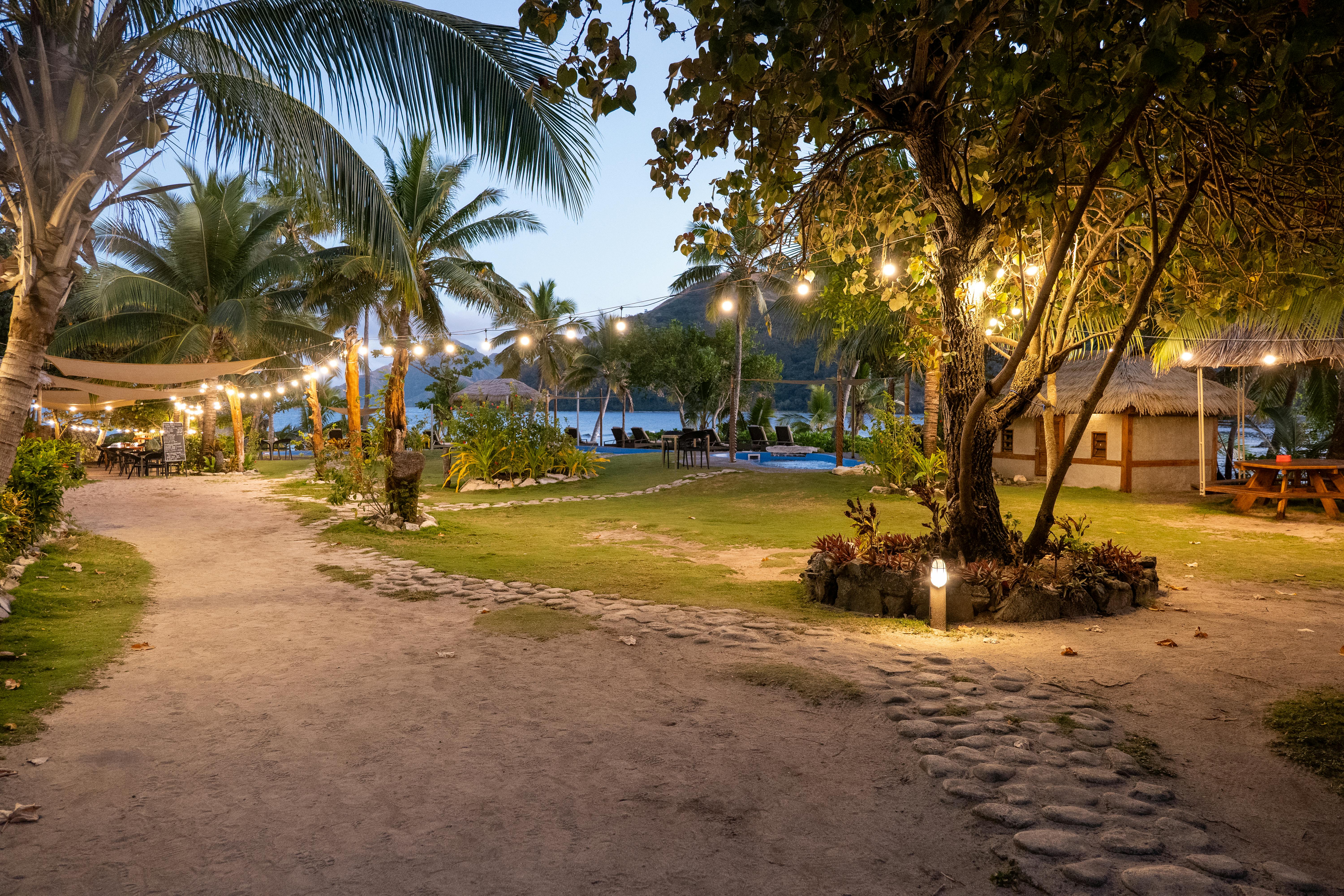 Charming evening view of a tropical resort pathway in Fiji, adorned with glowing string lights.