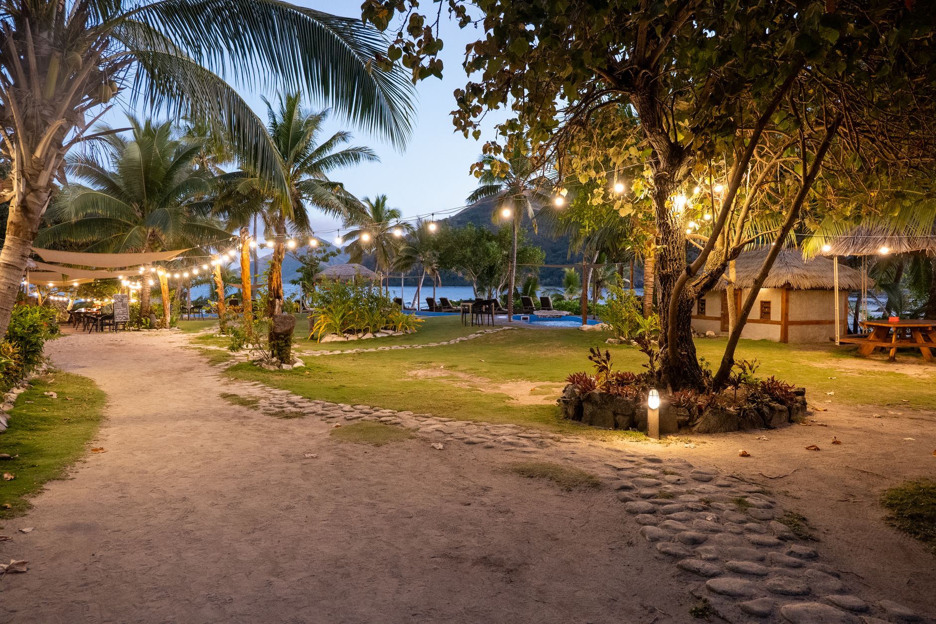 Charming evening view of a tropical resort pathway in Fiji, adorned with glowing string lights.
