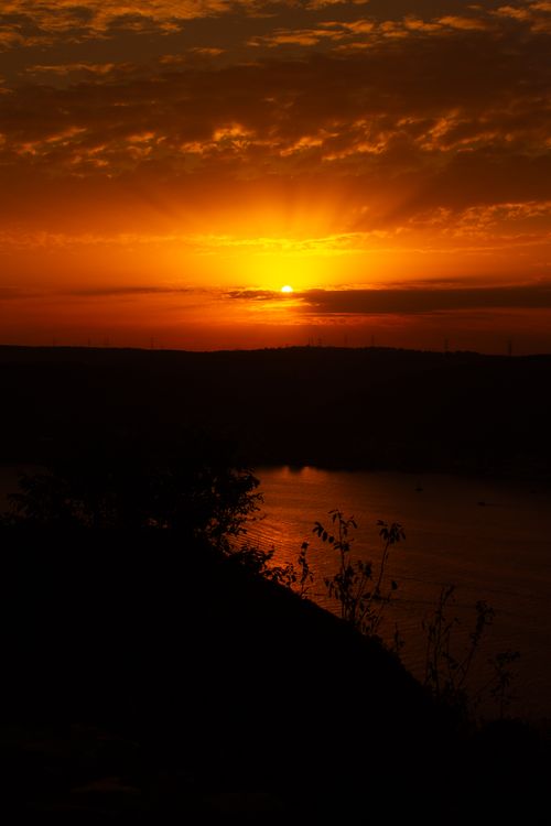 Free A breathtaking sunset over calm waters with vibrant orange and red hues. Stock Photo