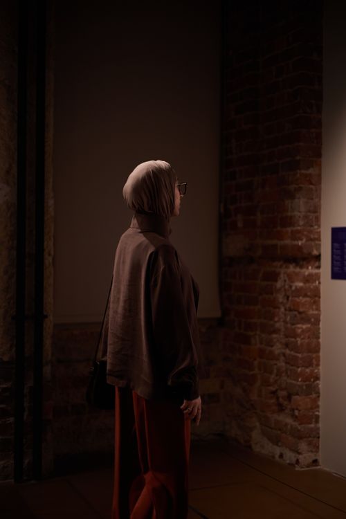 Free A woman in a headscarf observes a painting in a dimly lit Istanbul gallery. Stock Photo