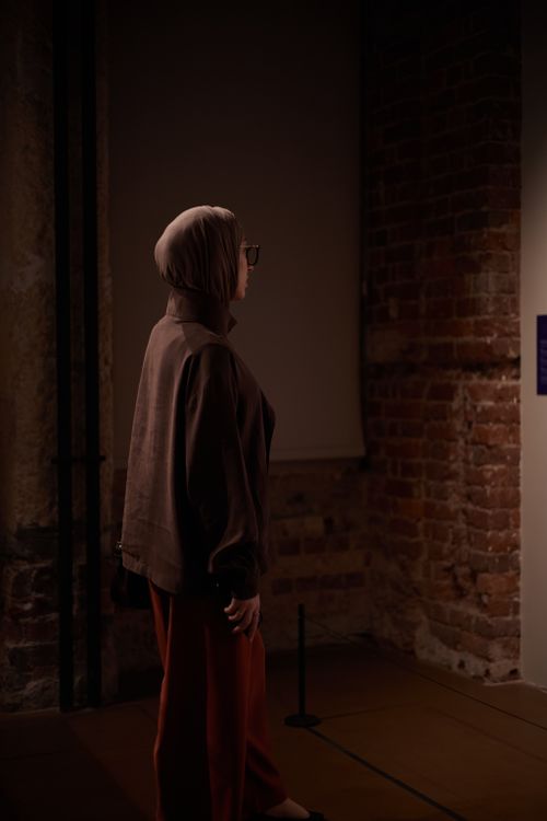 Free Side view of a woman in a hijab gazing at a gallery exhibit in Istanbul, creating a thoughtful atmosphere. Stock Photo