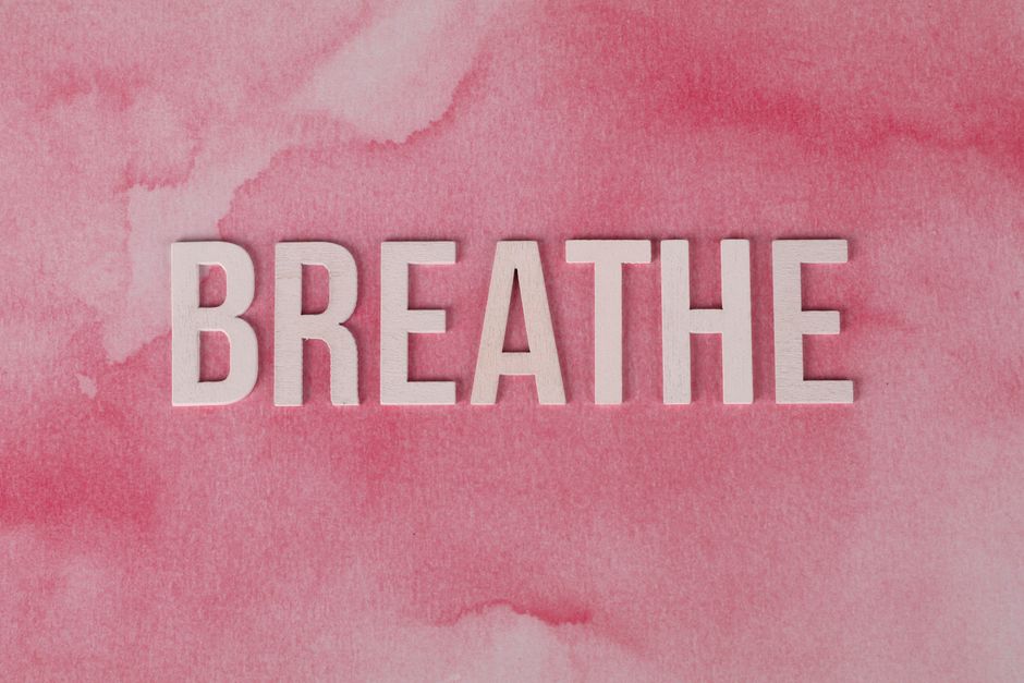Motivational 'Breathe' text on a pink watercolor background, promoting relaxation and mindfulness.