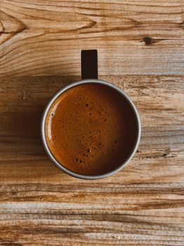 Aerial shot of a coffee cup on wooden table, optimal for cozy and warm lifestyle themes.