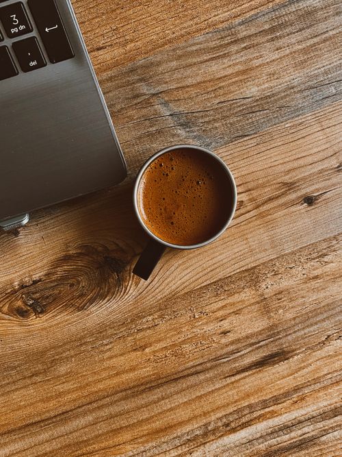 Free A cup of Turkish coffee beside a laptop on a rustic wooden table. Stock Photo
