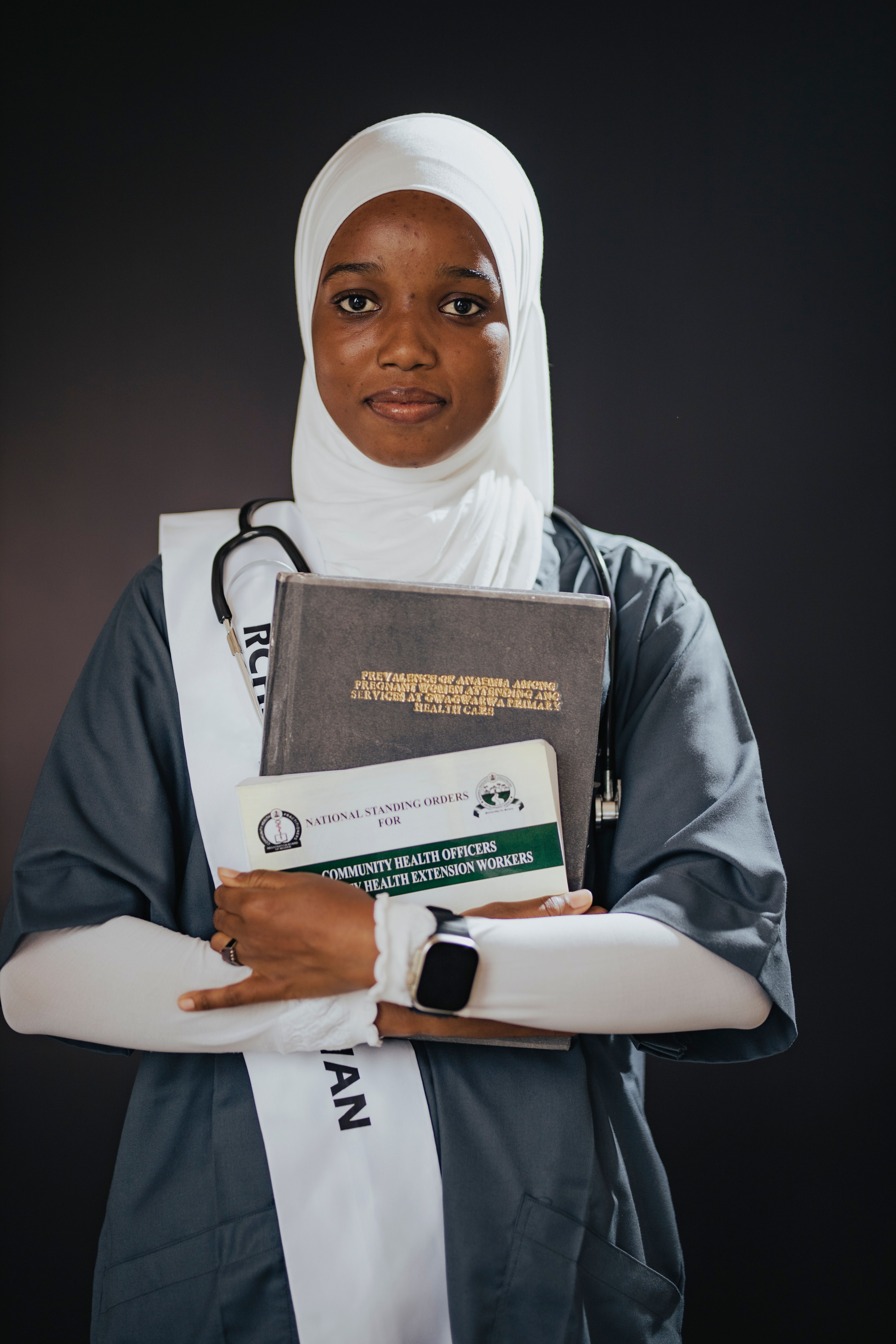 Healthcare Student in Graduation Attire with Books · Free Stock Photo