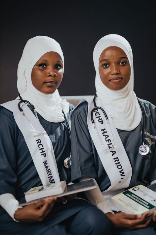 Free Two female medical graduates in traditional attire celebrating their achievements indoors. Stock Photo