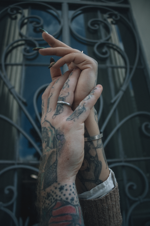 Free Close-up of tattooed hands intertwined with a creative background. Stock Photo