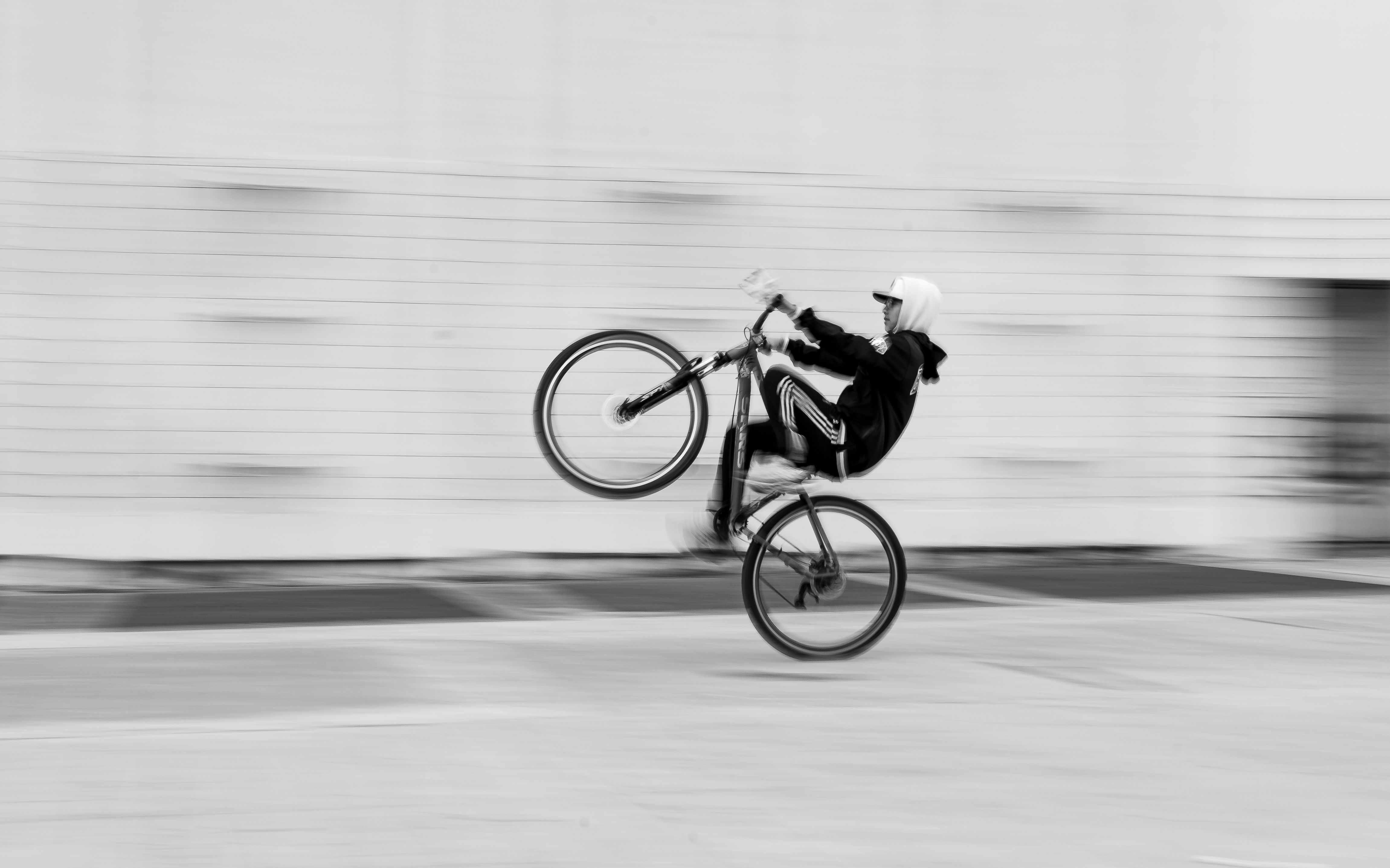Captured motion in black and white as a cyclist performs a wheelie, embodying urban energy.