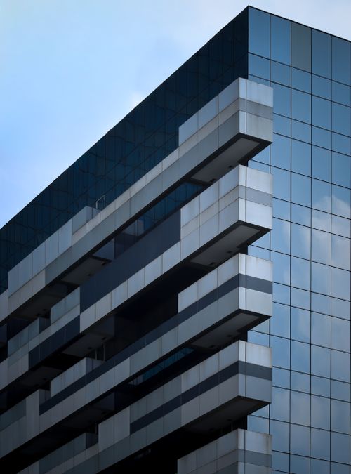 Free Striking modern office building with reflective glass facade against blue sky. Stock Photo