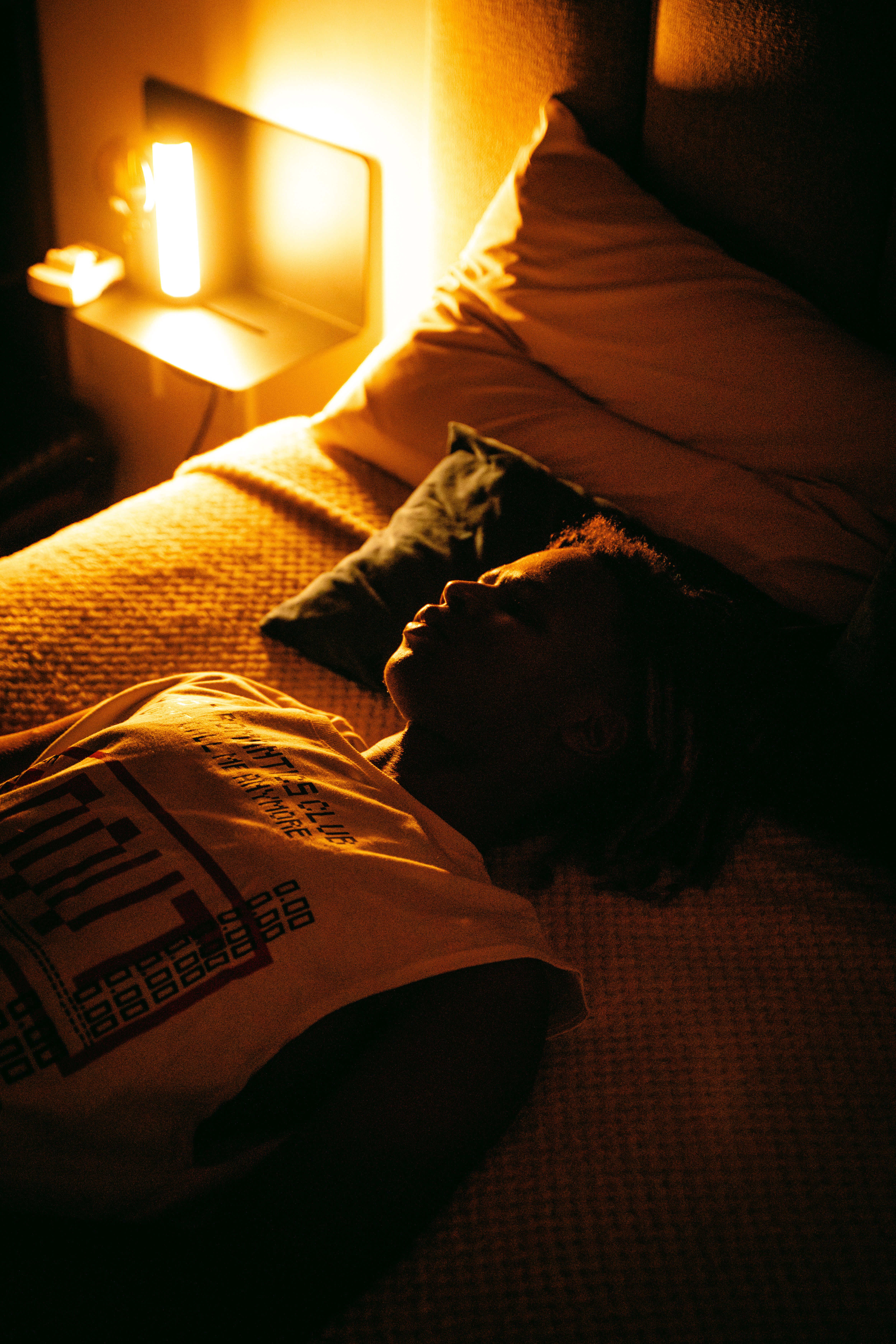 Person peacefully sleeping on bed with warm ambient lighting.