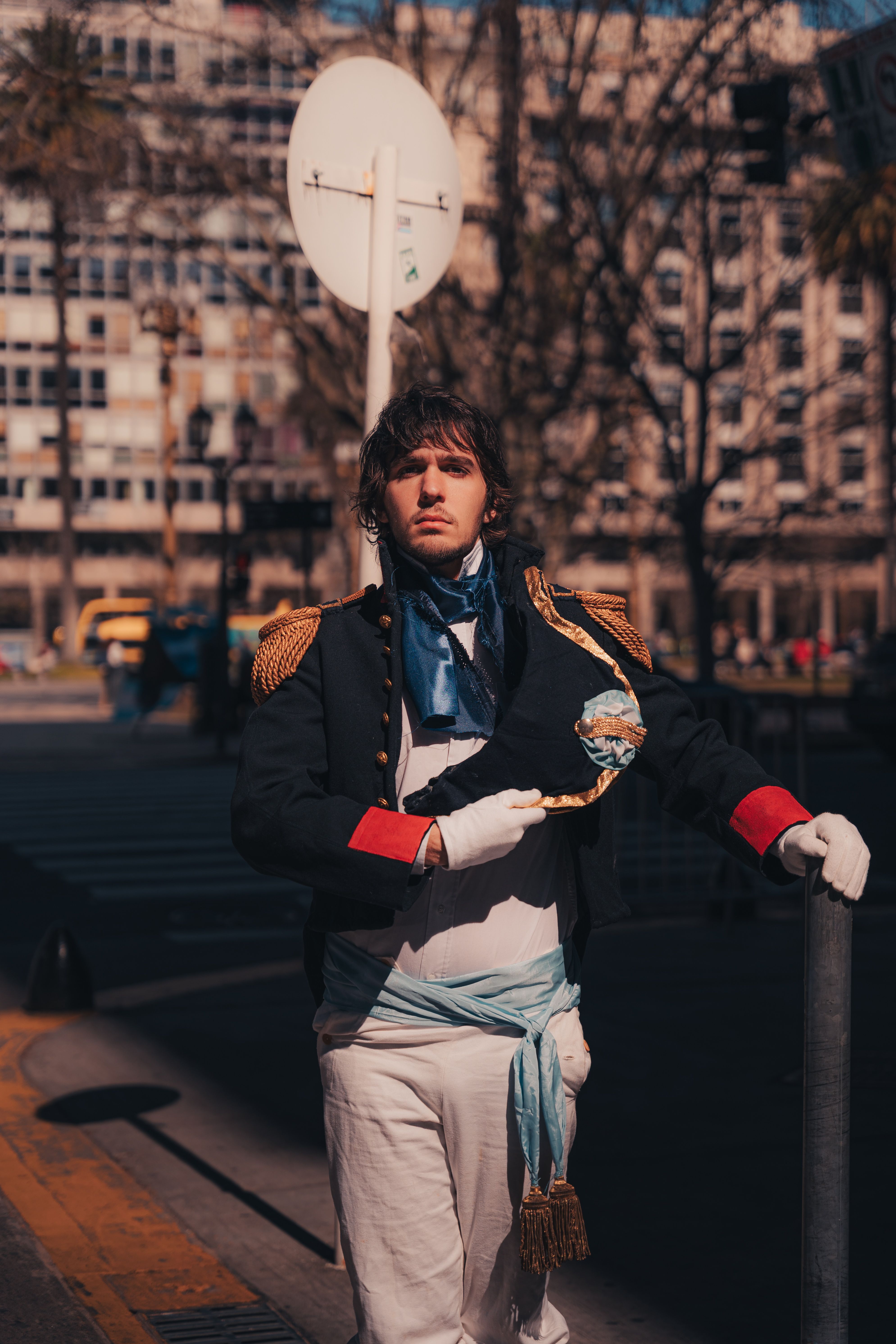 Man in historical military costume posing on city street in daylight.
