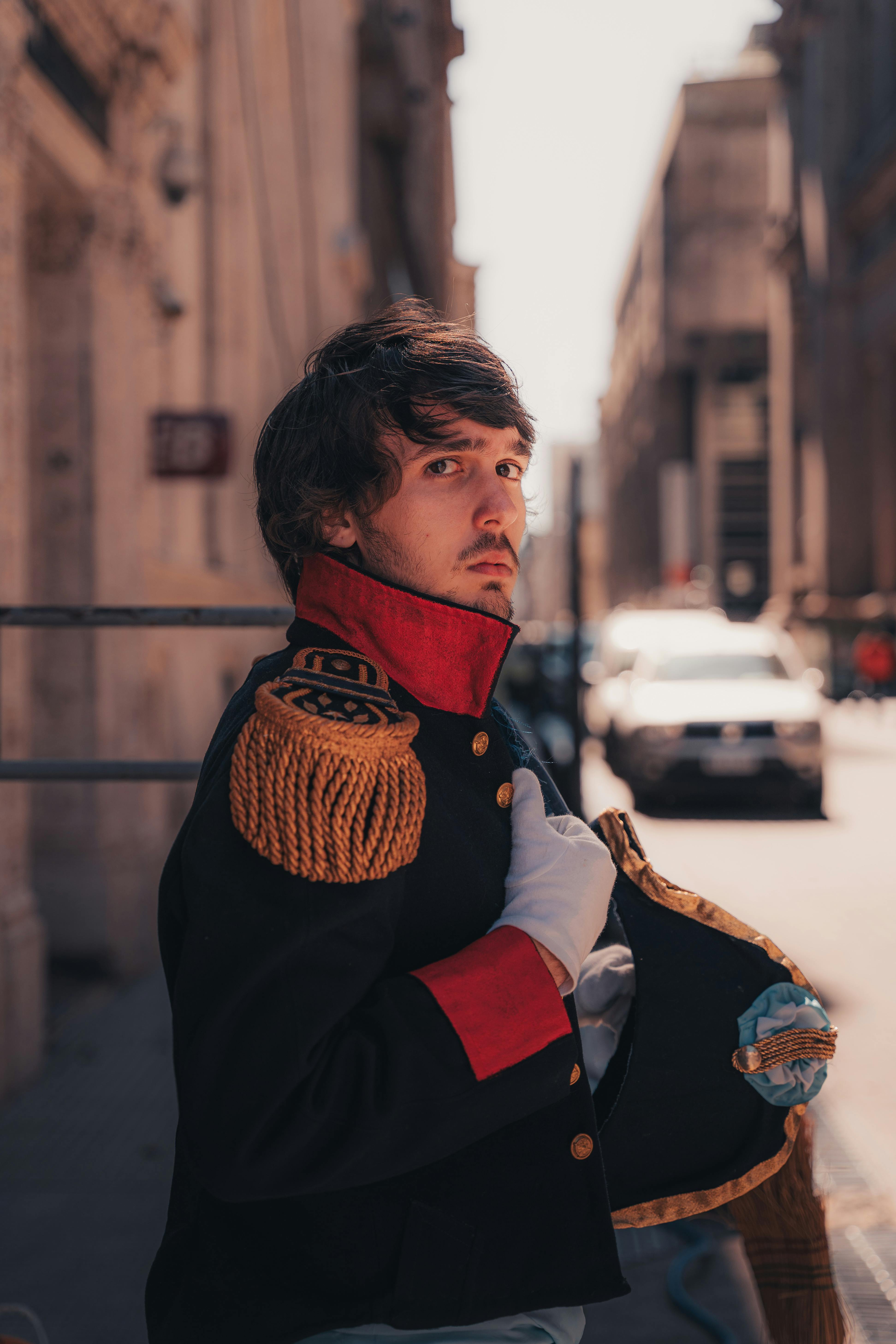 Gratuit Un homme portant un uniforme de soldat historique se tenant avec confiance dans une rue lumineuse de la ville. Photos