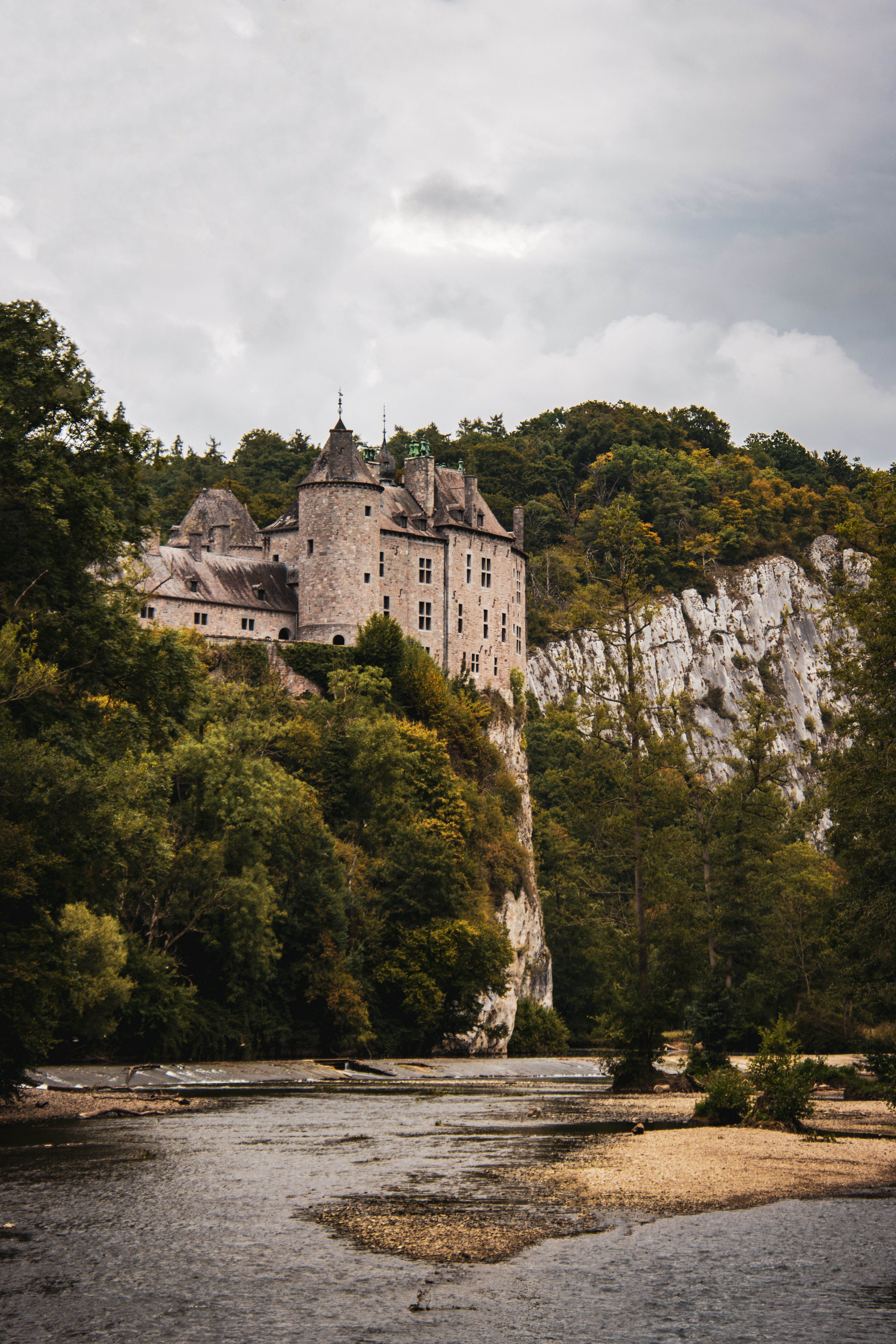 Picturesque view of a historic castle on a cliff above a river in Dinant, Belgium.