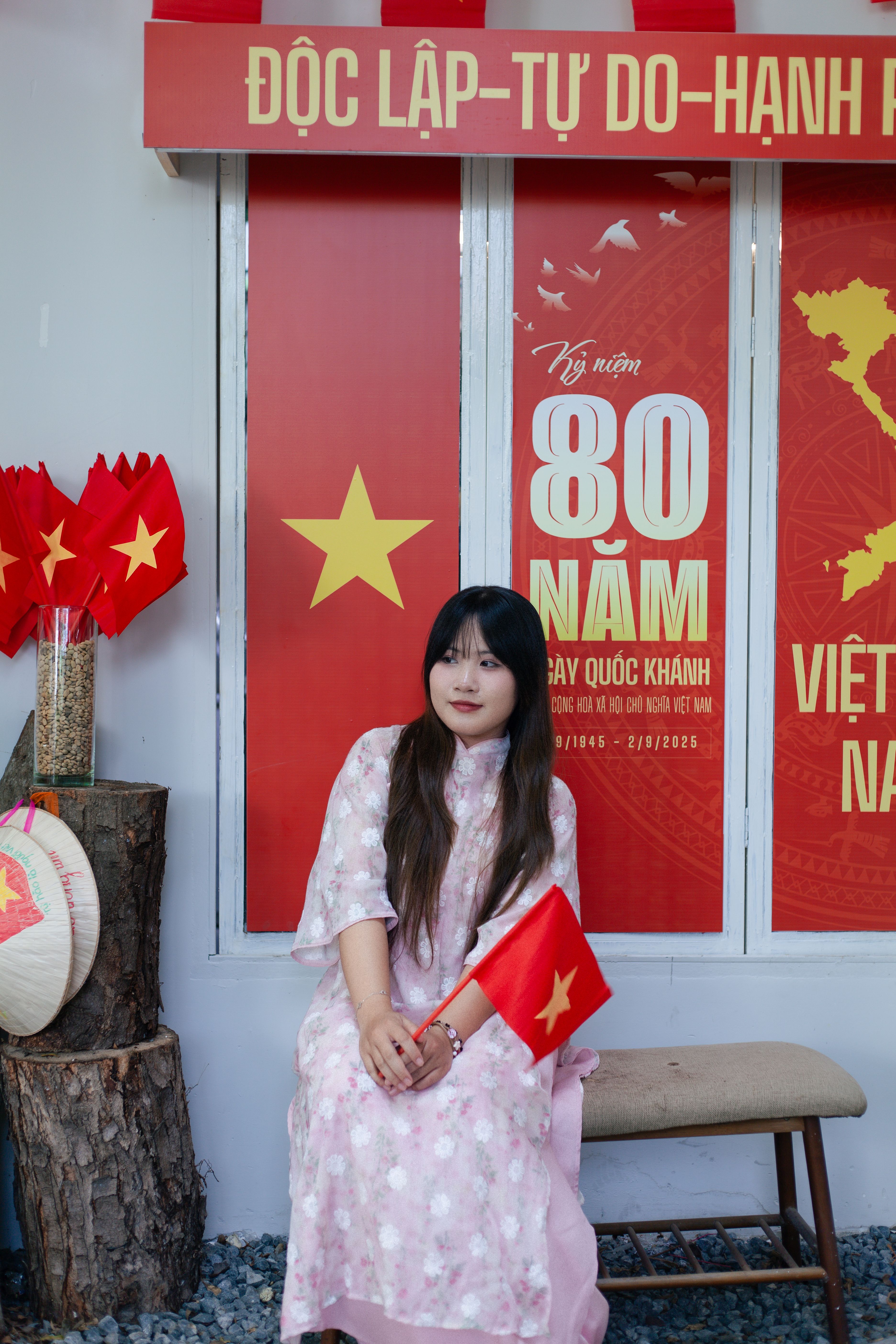 Vietnamese woman in traditional dress holding a flag, celebrating National Day.