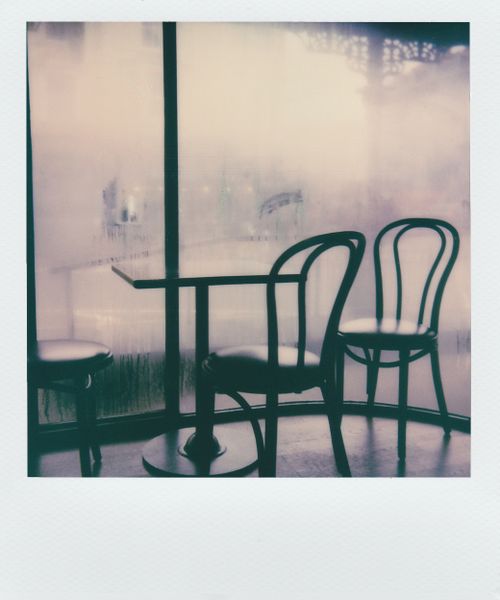 Free A serene cafe corner featuring antique chairs and table by foggy glass windows, evoking warmth and nostalgia. Stock Photo