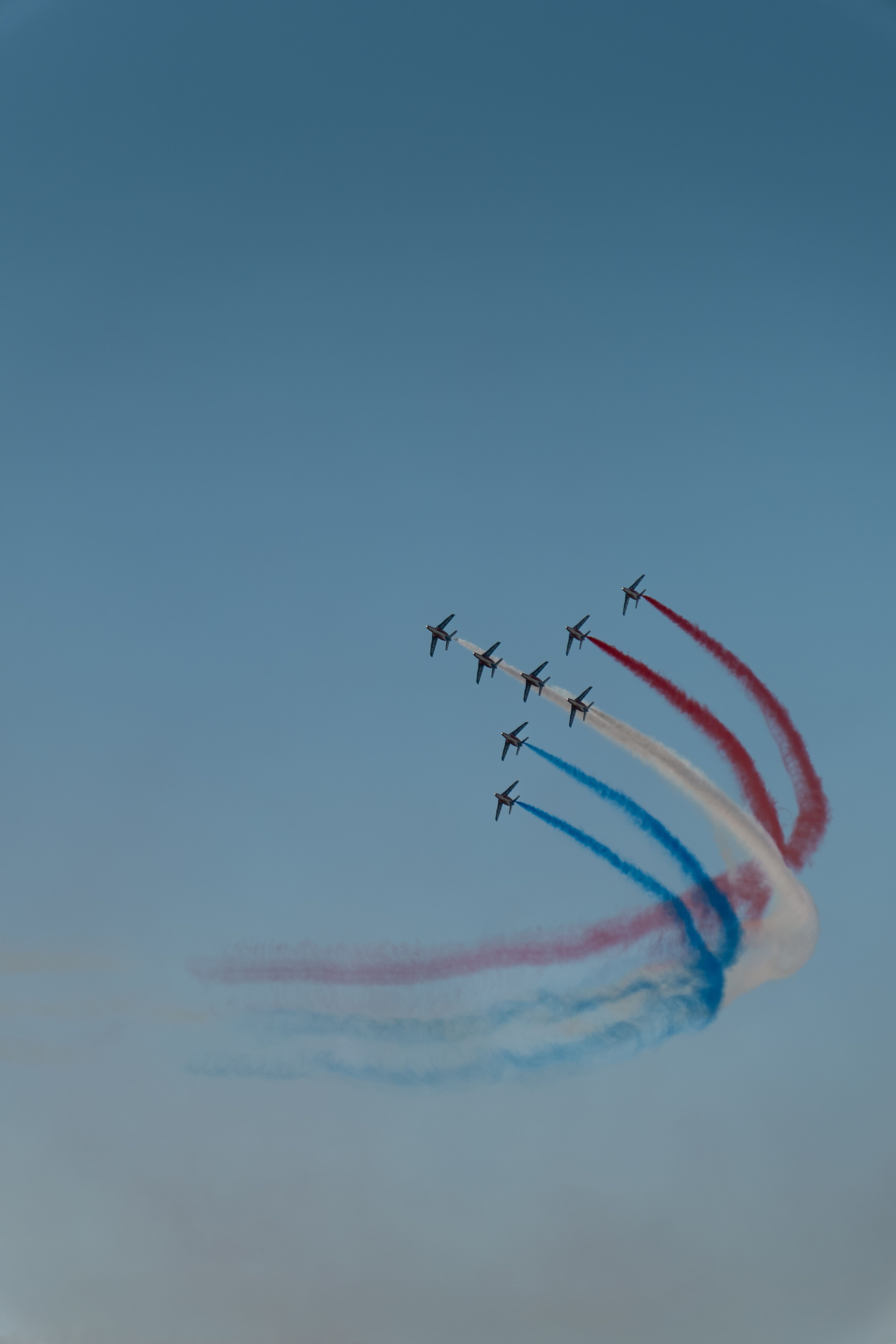 Aerobatic jets trailing colored smoke across the sky at an international airshow