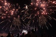 Silhouetted crowd watching a brilliant fireworks display lighting up the night sky.