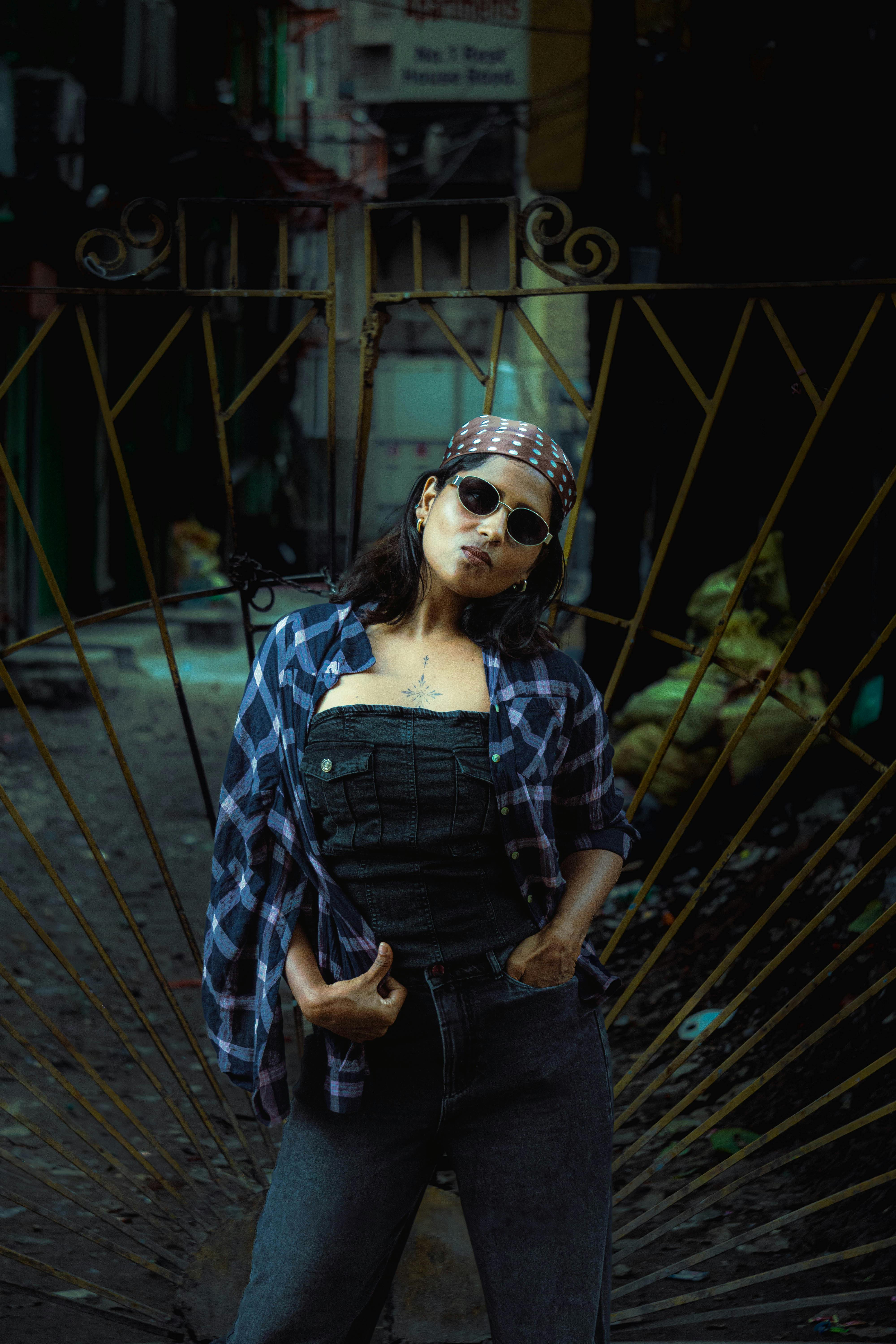 Fashionable woman in sunglasses posing confidently in a gritty urban alleyway.