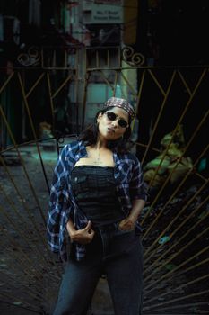 Fashionable woman in sunglasses posing confidently in a gritty urban alleyway.