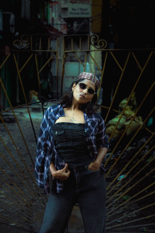 Free Fashionable woman in sunglasses posing confidently in a gritty urban alleyway. Stock Photo