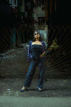 Stylish woman posing confidently in a grungy urban alleyway, exuding cool vibes.
