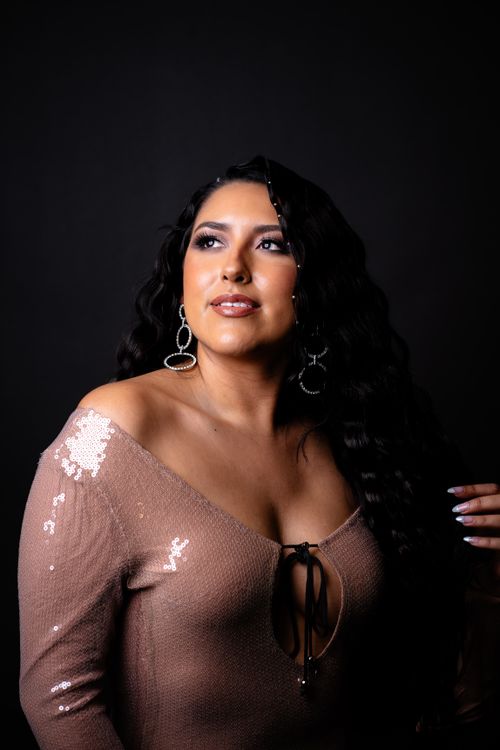 Free Portrait of a confident woman in a sequin dress, looking away with elegance. Stock Photo