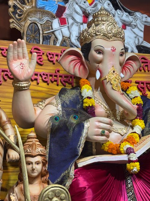 Free Colorful Lord Ganesha statue adorned with marigold garlands and peafowl feathers, perfect for festivals. Stock Photo