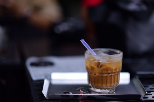 Free A close-up of an iced coffee in a glass with a straw on a metal tray, perfect for a summer day. Stock Photo