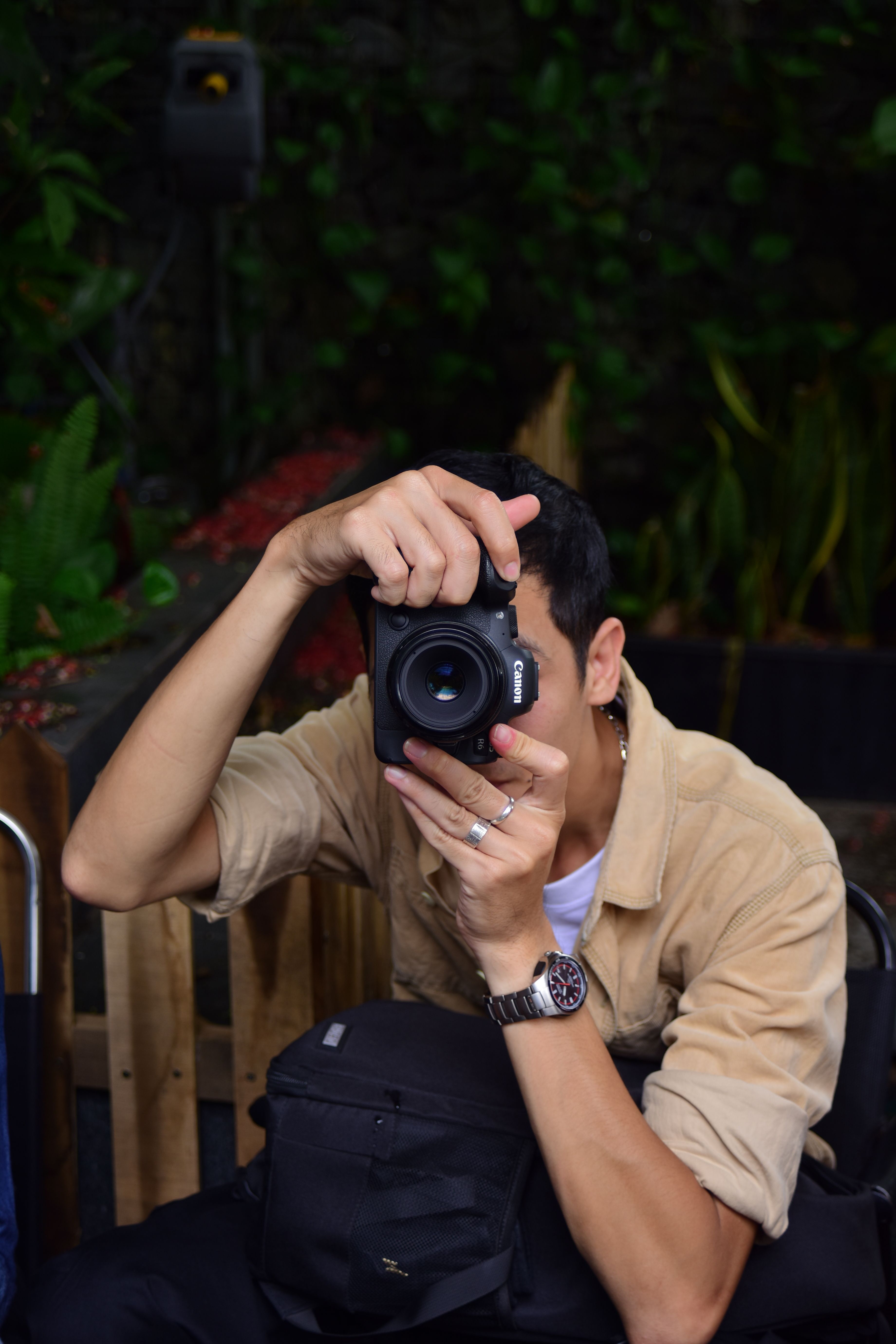 A man capturing a scene with a camera surrounded by greenery, creating an artistic vibe.